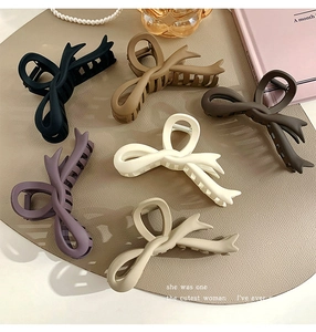 Flat lay of six matte large claw clips in assorted colors like brown, beige and black