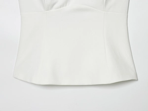 Détail du haut court blanc ajusté montrant la coupe de la taille et la texture de l'ourlet