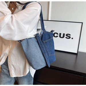 Detail of blue denim canvas bucket bag showing contrast stitching and external pocket