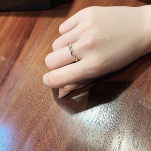 Close-up of golden twisted braid ring with clear zircon crystals on finger