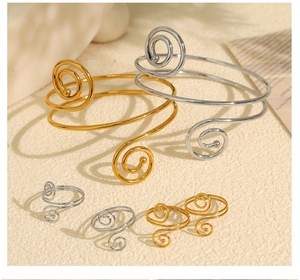 Detail view of gold and silver spiral rings and bracelets on a textured background