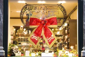 Detail of red glitter Christmas bow with pine cones, gold edges and bell charms