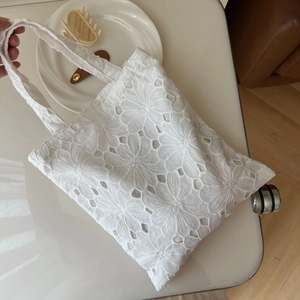 Detailed view of white eyelet floral embroidery and hollow-out lace on cotton tote bag