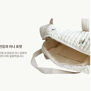 Detail view of beige quilted diaper bag interior with lining and small inner pocket