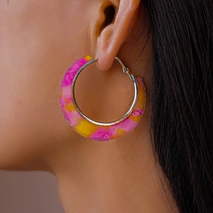 Macro side view of a model wearing large pink and yellow marbled acetate hoop earrings