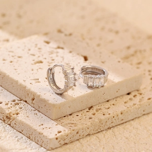 Macro detail showing S925 hallmark on silver hoop earrings with rectangular zircons