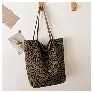 Close-up of leopard print tote bag hanging on a wooden hook against a white wall