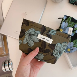Detail of dark green floral jacquard mini fabric pouch with white simple wish label