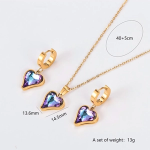 Golden necklace and hoop earrings set featuring purple crystal heart pendants on white back