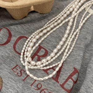 Elegant multi-layer 925 silver necklace with white pearls on a minimalist background