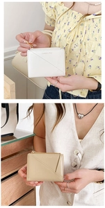Detail of white and khaki faux leather zip wallets with star branding and geometric stitching