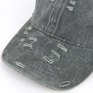 Detailed view of distressed dark grey washed denim baseball cap with vintage frayed holes