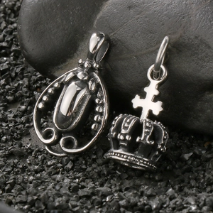 Vintage silver crown cross pendant and oval gemstone necklace charms on stone background