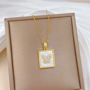 Detailed macro view of a gold square pendant with white shell and a diamond butterfly