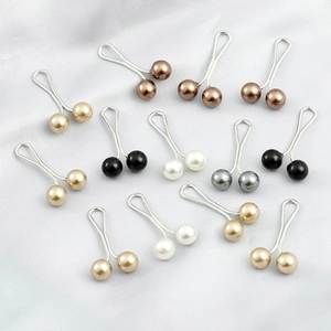 Multiple U-shaped pearl brooch clips in assorted colors on elegant white satin fabric