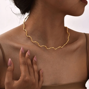 Close-up of elegant golden wavy choker necklace on a model showing continuous ripple design