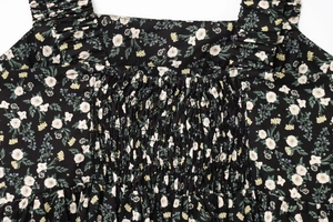 Detail of square neckline with smocked chest and ruffled straps on black floral dress