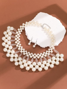 Detailed view of multi-layer pearl necklace and drop earrings on white stone base