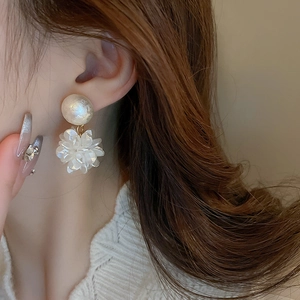 Boucles d'oreilles fleuries avec perles d'imitation et fleurs blanches sur un modèle