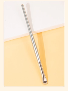 Détail du pinceau eye-liner ultra-fin argenté sur fond blanc et jaune vif