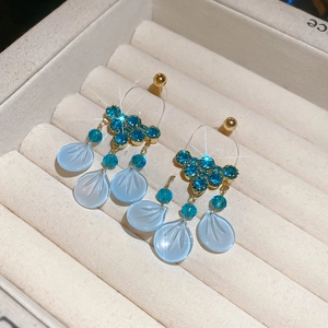 Detailed close-up of blue petal earrings with crystal accents in a velvet jewelry box
