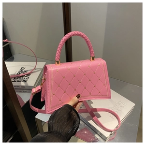 Detail of pink quilted PU leather handbag with golden heart charm and top handle