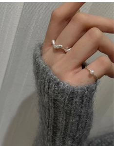 Close-up of minimalist S925 silver wave ring and white pearl ring worn together