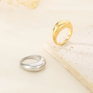 Detail of polished gold and silver domed rings on a minimalist textured surface