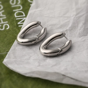 Minimalist silver oval hoop earrings with polished geometric metal on a textured background