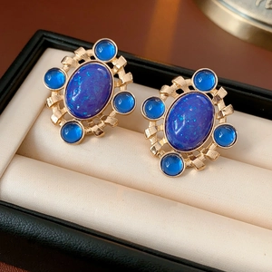 Macro shot of vintage style earrings with blue gemstones in gold setting on velvet box