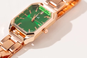 Detail of square rose gold quartz watch featuring a green dial and diamond accents