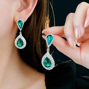 Dettaglio di orecchini a goccia in argento con pietre verdi e diamanti bianchi brillanti