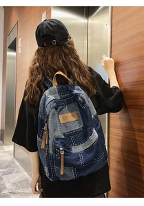 Close-up of denim backpack featuring vintage patchwork design and premium leather zipper