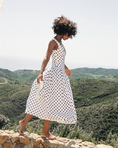 Elegante witte polkadotted jurk met V-hals en vloeiende A-lijn rok in een buitenomgeving