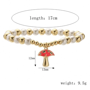 Detailed view of bead bracelet with gold accents and a red mushroom charm with dimensions