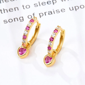 Macro shot of gold heart earrings with pink zircons and small white gemstones