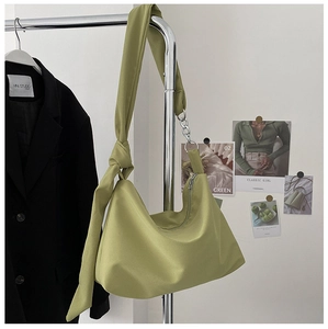 Detail of green hobo bag featuring knotted shoulder strap and smooth metal zipper closure