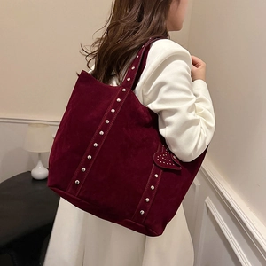 Burgundy suede tote bag with silver studs and heart pendant shown on model shoulder