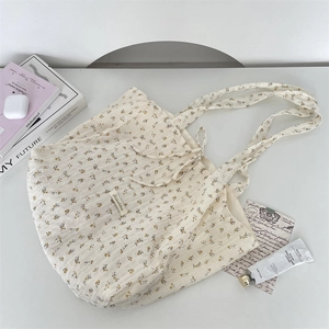 Detail of floral canvas tote bag with bow tie and daily essentials on a minimalist desk