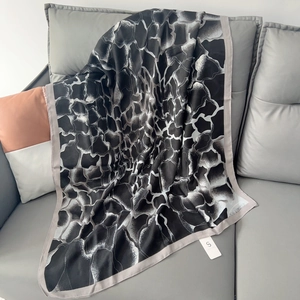 Detailed texture of black and white abstract silk scarf draped elegantly on a grey sofa
