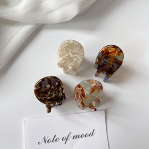 Mini acetate hair claw clips set in marble and tortoiseshell patterns on white background
