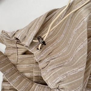 Detail of khaki striped canvas tote bag fabric with drawstring and adjustable toggle buckle