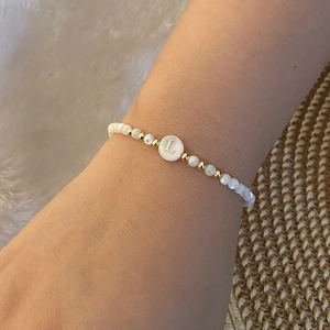Detail of beaded alphabet bracelet with letter L pearl and golden spacer accents