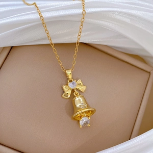 Elegant gold bow and bell pendant necklace with crystals on soft silk background