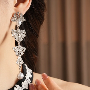 Close-up of dangling silver tassel earrings with sparkling rhinestones and white pearls