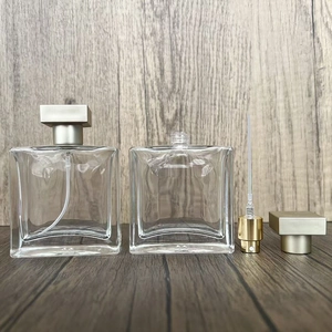 Detail view of disassembled square glass perfume bottles with metallic spray pumps and caps