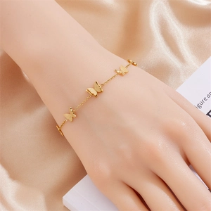 Detail of gold-plated butterfly bracelet on champagne satin featuring delicate charms