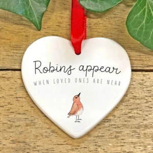 Close-up of heart ceramic ornament with red ribbon on rustic wood background