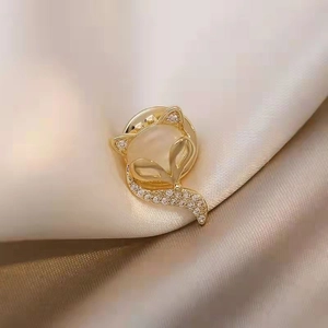 Detailed view of fox brooch with opal and sparkling crystals on golden alloy