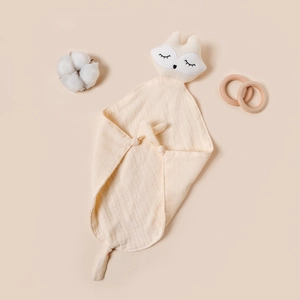 Detailed view of beige muslin baby comforter with fox head embroidery and knotted corners